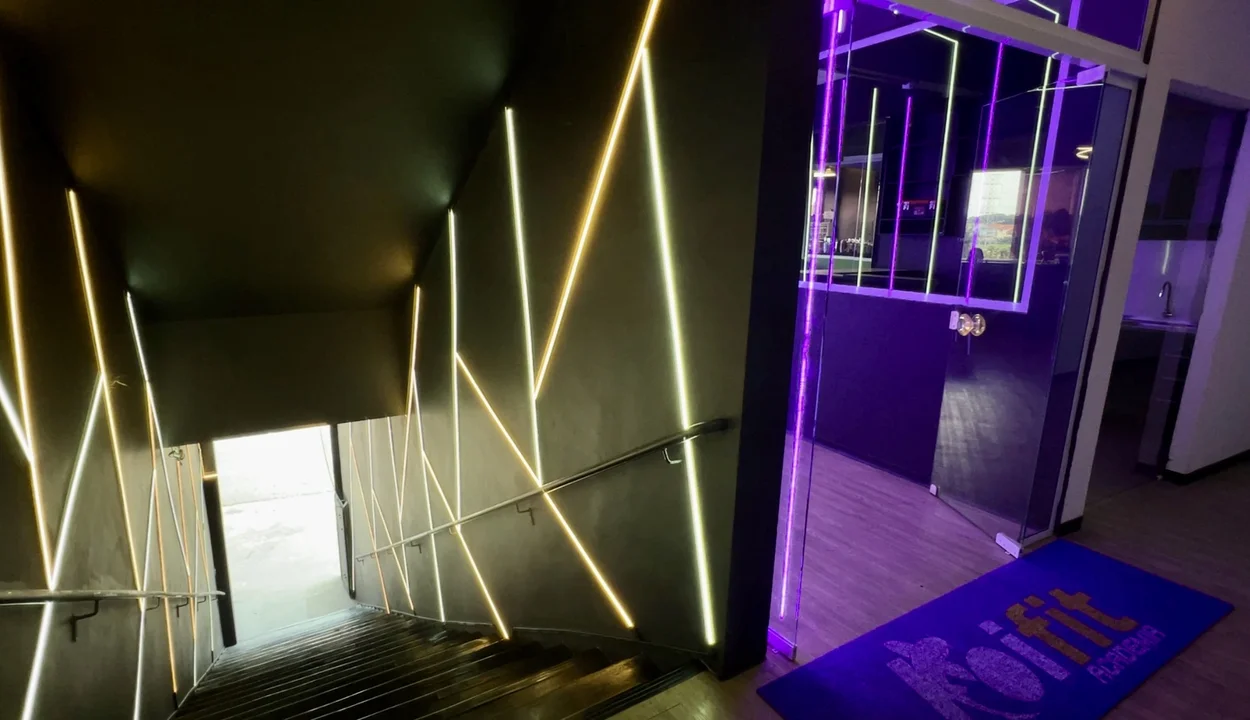 Corredor de entrada com iluminação neon na identidade KOIFIT.