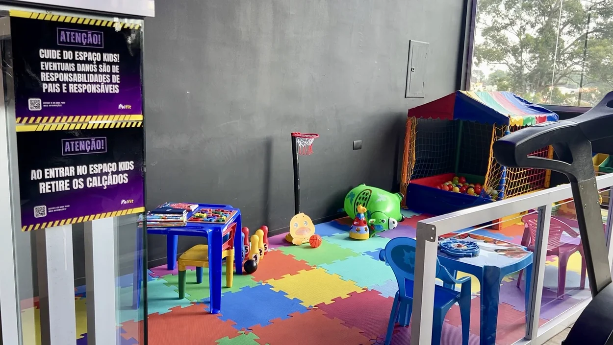 Espaço kids com brinquedos e piso emborrachado colorido.
