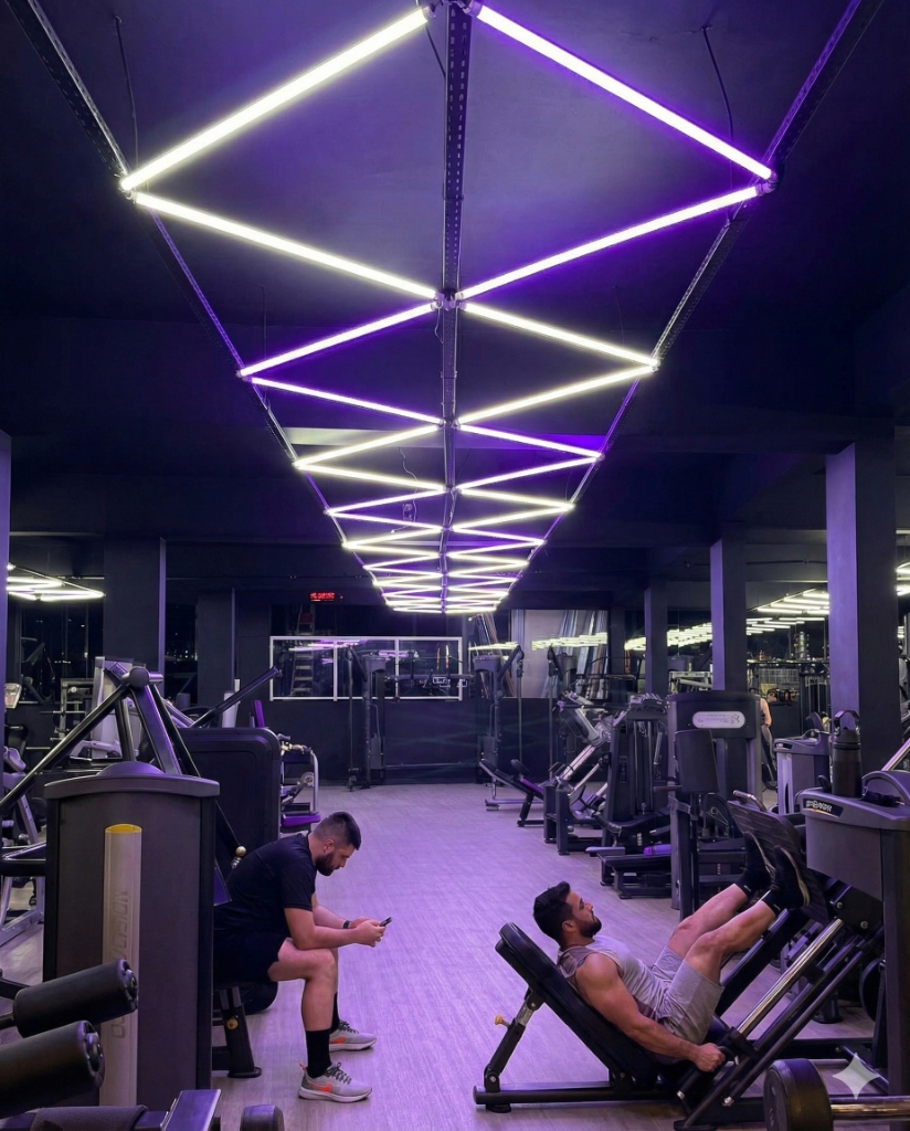 Interior da academia Koi Fit com iluminação neon roxa e equipamentos premium